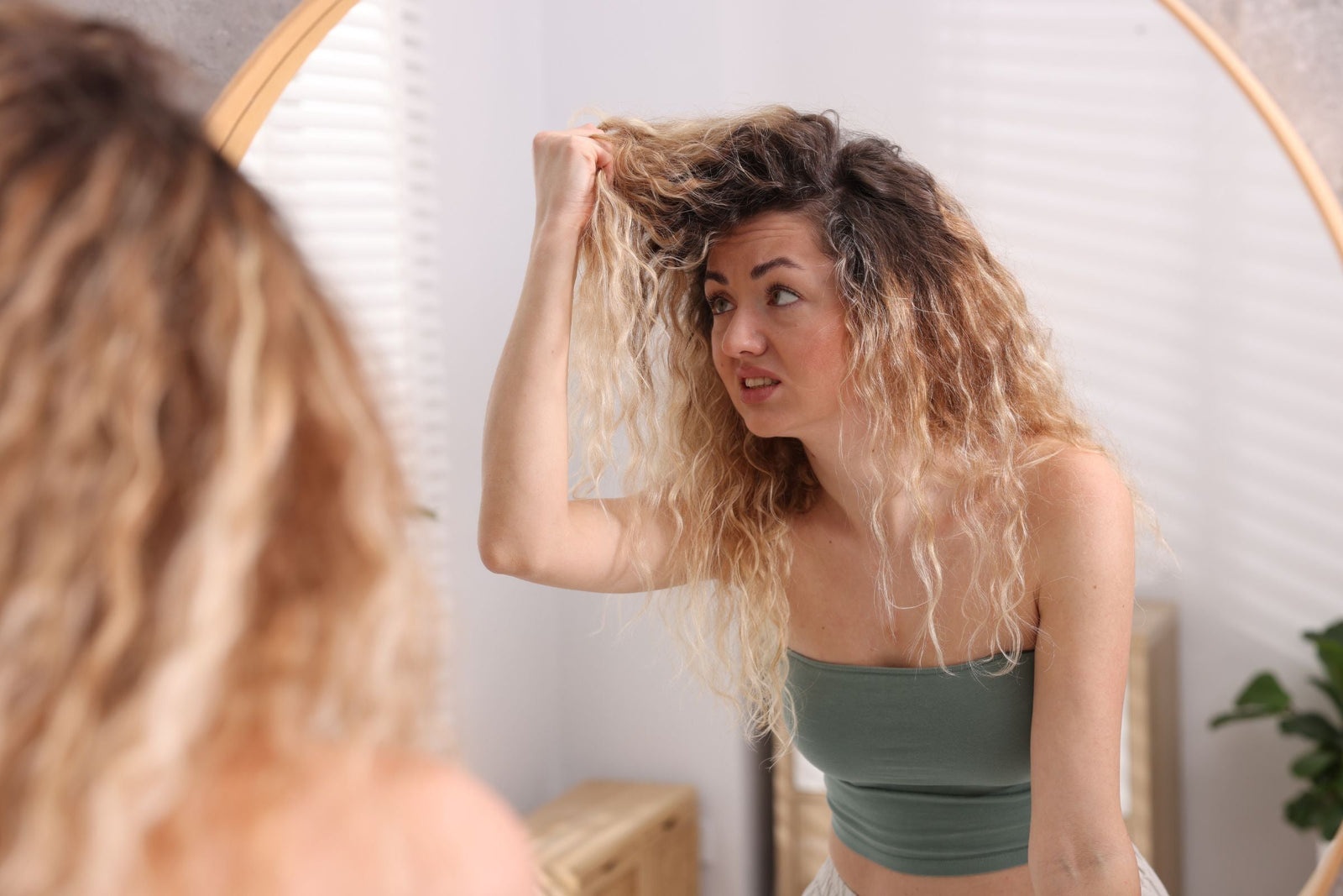 Women looking at her dry damaged hair in the mirror 